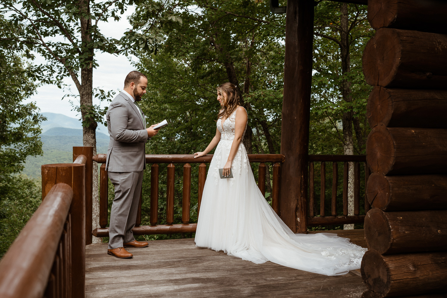 Groom reads his vows to his bride before their elopement with a blue ridge mountain view in the background