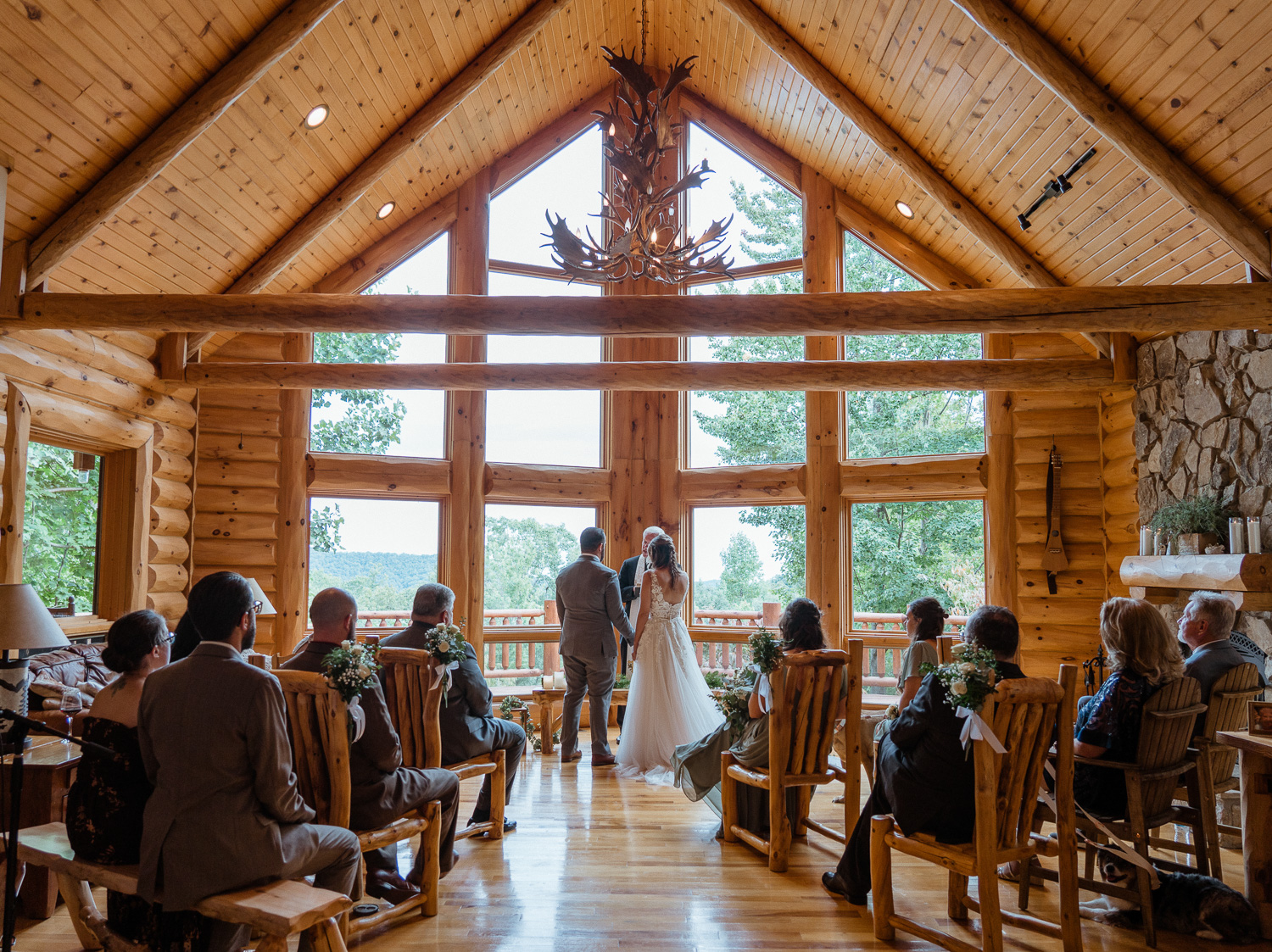 Bride and Groom hold hands during their elopement ceremony in a log cabin ceremony surrounded by loved ones