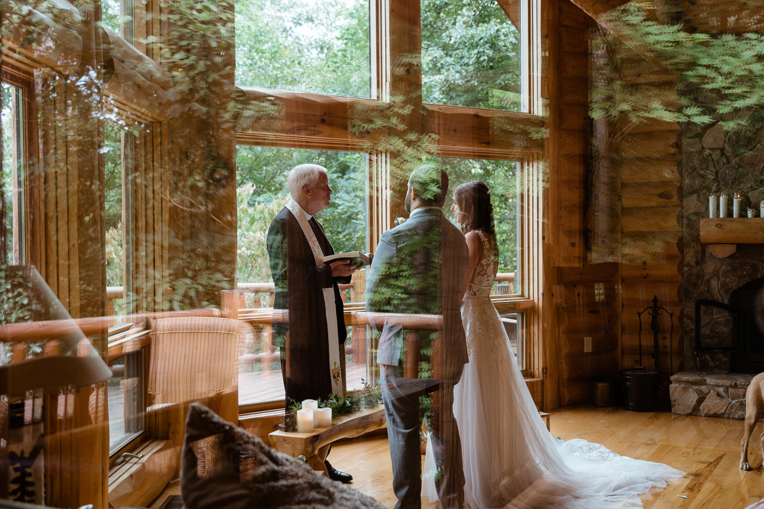 The couple and their officiant can be seen through a window with the reflection of leaves at their Asheville elopement