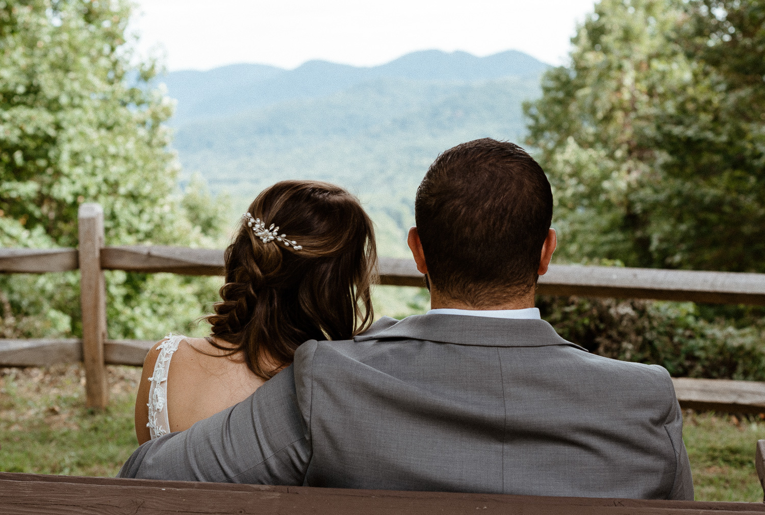 Bride and groom sit close in front of a beautiful blue ridge mountain view in Asheville