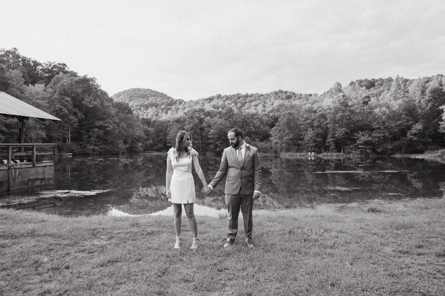 Couple hold hands in front of a lake after their elopement ceremony