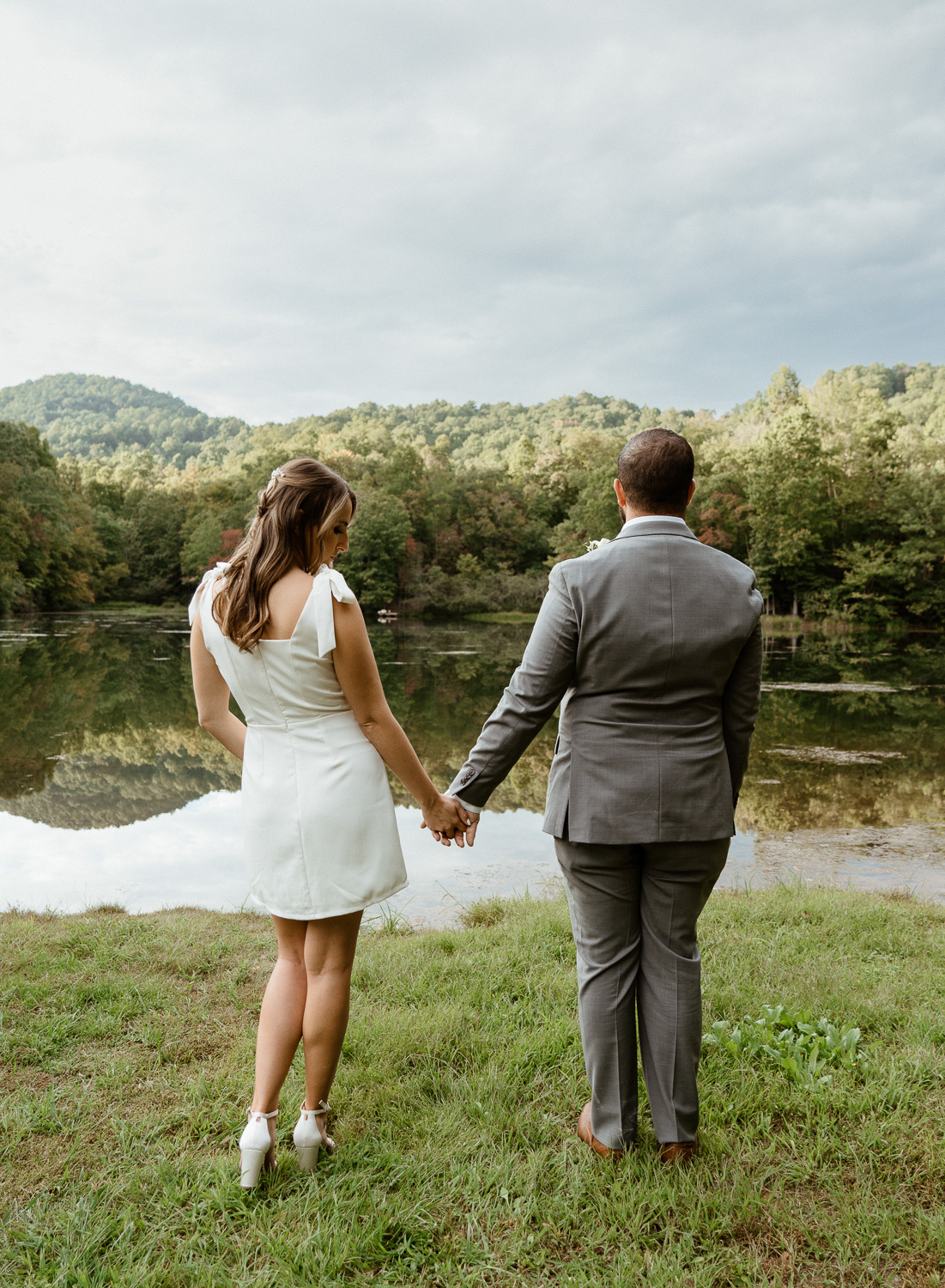 Asheville elopement couple holding hands in front of lake