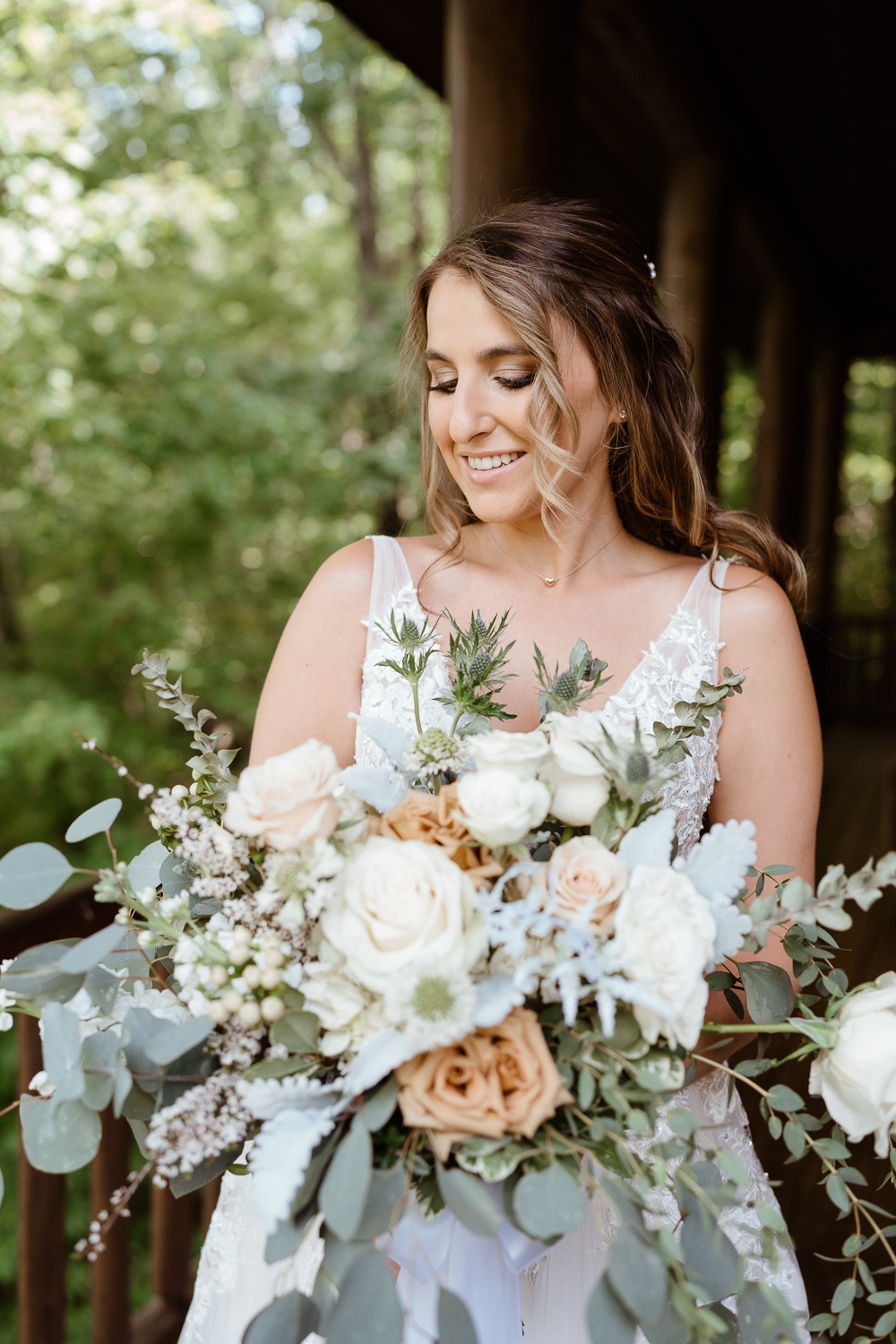Bride smiles at bouquet before her cabin elopement ceremony