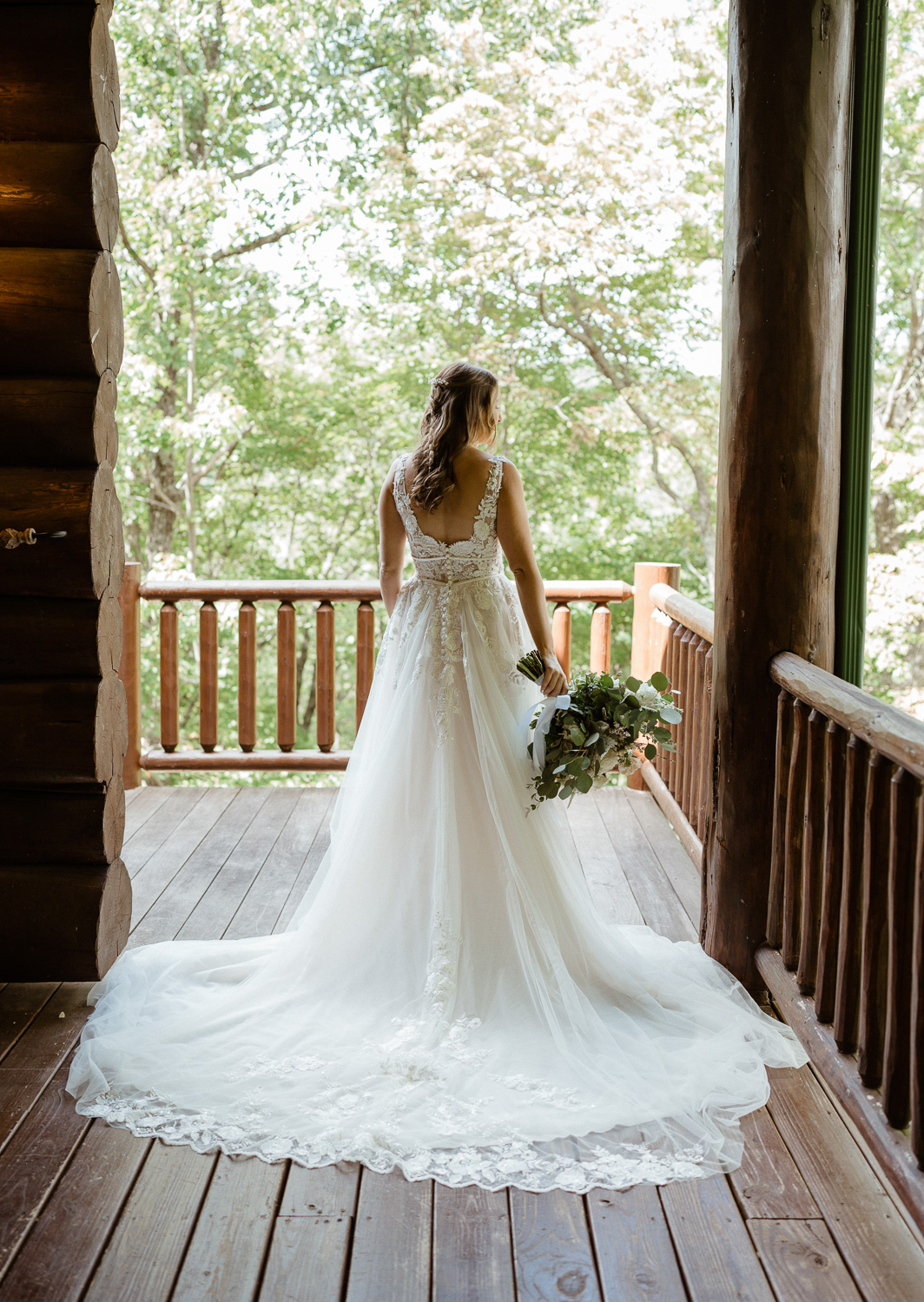 Bride shows off the back of her dress and bouquet